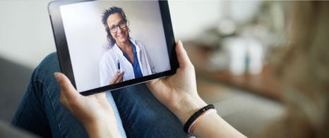Mujer sosteniendo una tablet y hablando con una profesional de la salud